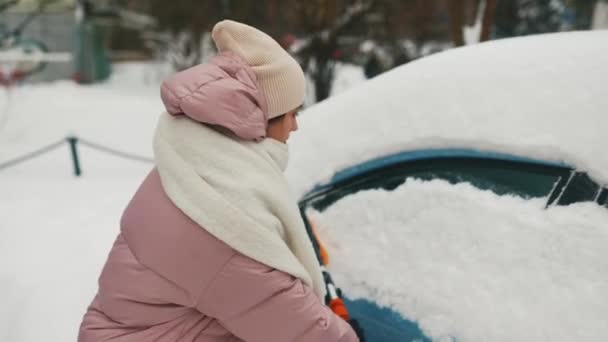 Kvinnan tar bort snö från bilen — Stockvideo