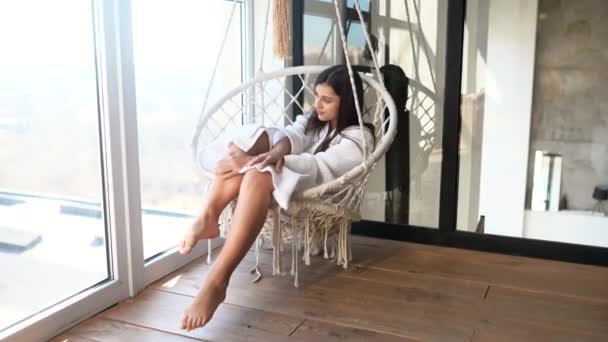 Sexy brunetka w biały szlafrok na wiszące krzesło — Wideo stockowe