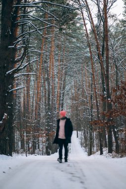 Ormanın ortasında, karla çevrili bir yolda duran bir adam.