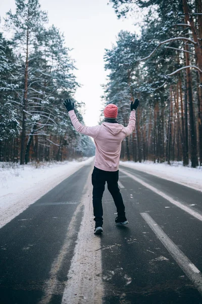 Cara de pé na estrada no meio da floresta, cercado por neve — Fotografia de Stock