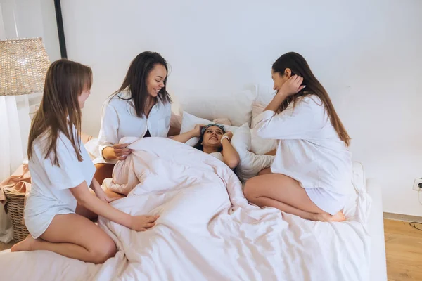 Positieve jonge meisjes vrouwen vrienden binnen op bed op de kip partij thuis. — Stockfoto