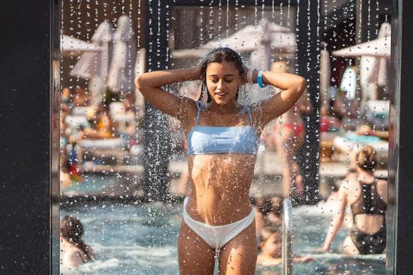 Hermosa chica en traje de baño duchándose bajo el agua en la playa Resort. —  Fotos de Stock
