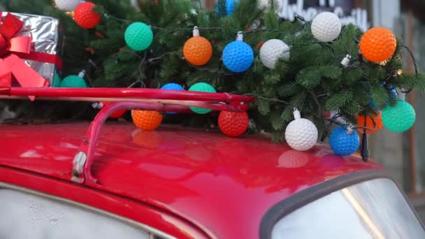 Coche retro rojo con un abeto de árbol de Navidad atado al techo. — Vídeo de stock