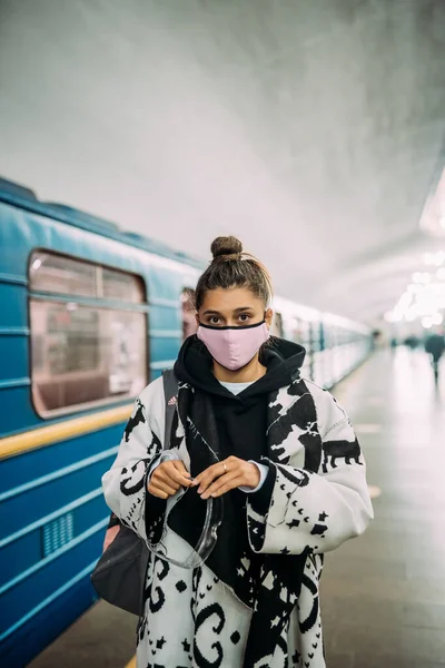 Молодая женщина, стоящая на станции в медицинской защитной маске — стоковое фото