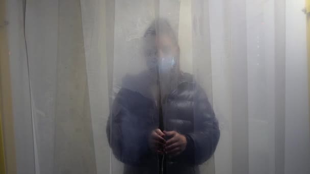 Una chica con una máscara protectora sale de la cámara de desinfección — Vídeos de Stock