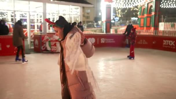 Люди любят кататься на коньках на улице вокруг елки на катке. — стоковое видео