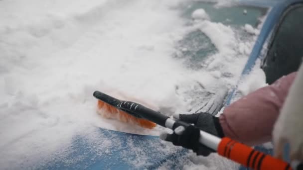 Vrouw verwijdert sneeuw uit auto — Stockvideo