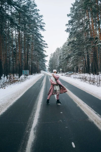 Retrato de uma bela mulher caucasiana em uma estrada através da floresta nevada — Fotografia de Stock