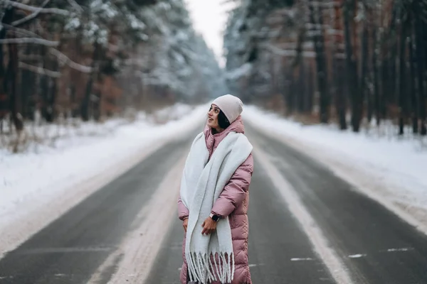 Porträt einer schönen kaukasischen Frau auf einer Straße durch verschneiten Wald — Stockfoto