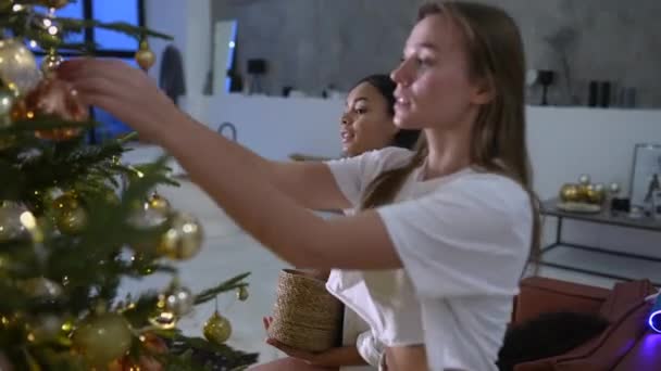 Ziemlich attraktive Frauen schmücken den Weihnachtsbaum mit Kugeln — Stockvideo