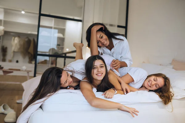 Chicas jóvenes positivas mujeres amigos en el interior de la cama en la despedida de soltera en casa. — Foto de Stock
