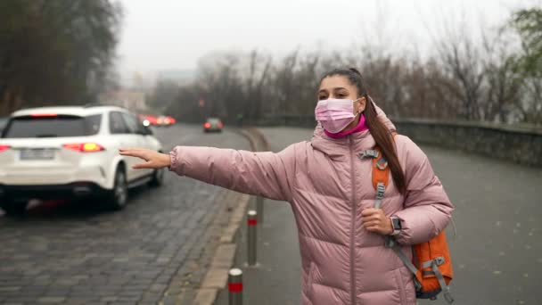 Mujer joven de pie en la carretera al aire libre levantando la mano a un lado la captura de taxi — Vídeos de Stock