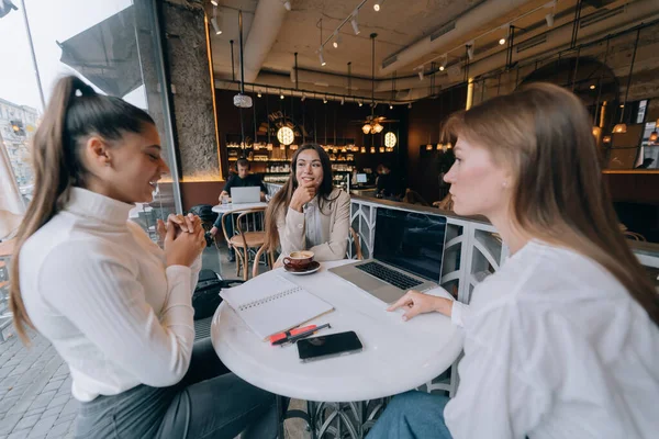 Eine Gruppe von Freundinnen in einem Café, die an einem Projekt arbeiten — Stockfoto