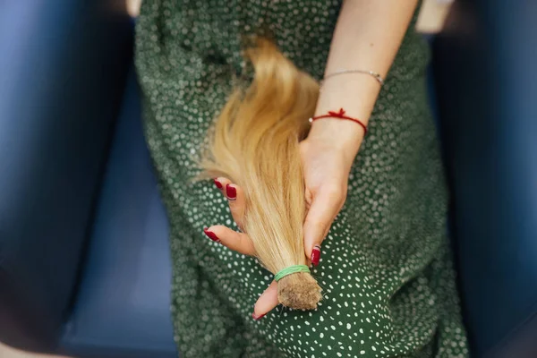 Молода жінка тримає її свіжо порізане довге коричневе волосся в хвостах — стокове фото