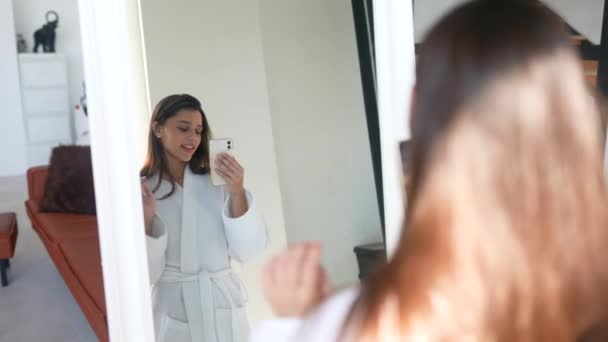 Junge Frau im Bademantel vor einem Spiegel. — Stockvideo