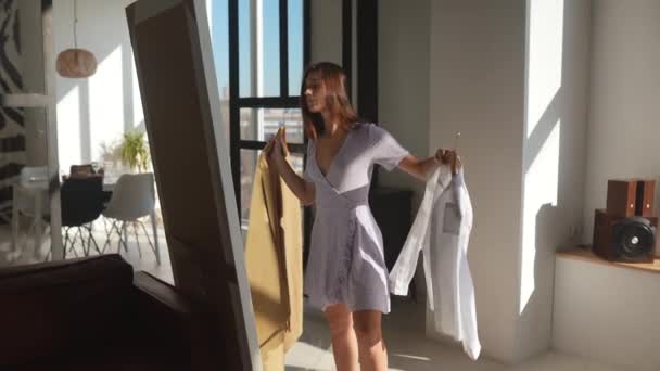 Gyönyörű lány kipróbálás ruha a szobában — Stock videók