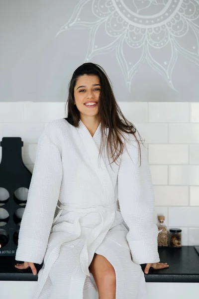 Elegan tersenyum wanita dalam mantel putih berpose di dapur — Stok Foto