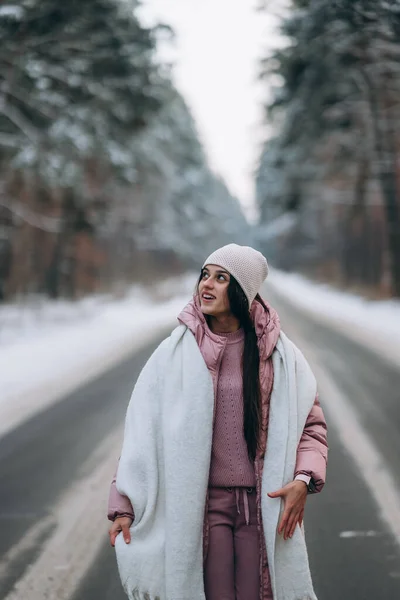 Retrato de uma bela mulher caucasiana em uma estrada através da floresta nevada — Fotografia de Stock