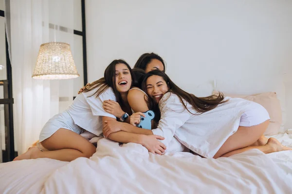 Θετικές νεαρές κοπέλες φίλες σε εσωτερικούς χώρους στο κρεβάτι στο κοτοπουλάδικο στο σπίτι. — Φωτογραφία Αρχείου
