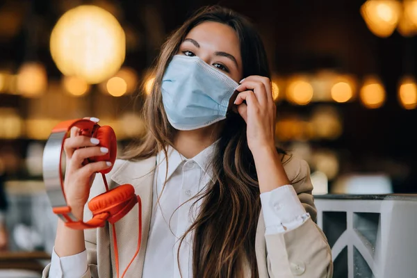 Девушка в кафе, снимает защитную медицинскую маску — стоковое фото