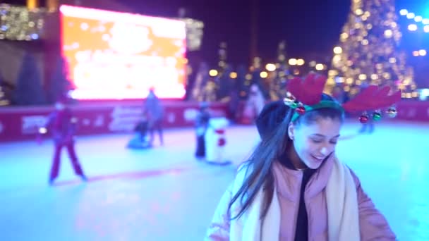 La gente disfruta patinaje sobre hielo en la calle alrededor del árbol de Navidad en pista de patinaje. — Vídeos de Stock