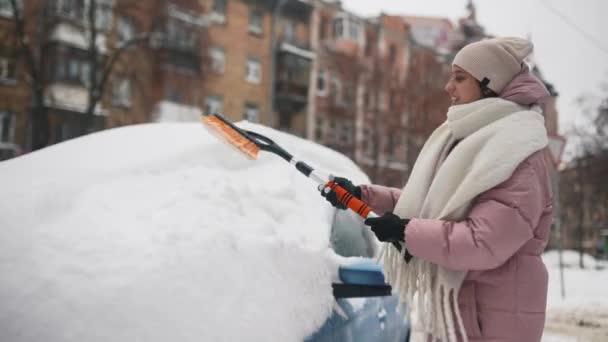 Femme enlevant la neige de la voiture — Video