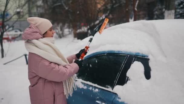 Жінка знімає сніг з машини — стокове відео