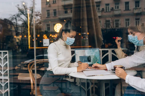 Друзья девушки познакомились в кафе. Наденьте защитные маски. — стоковое фото