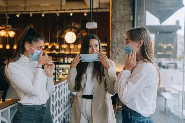 Mulheres brancas tirando uma máscara médica em um café — Fotografia de Stock