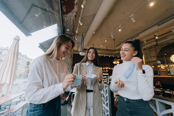 Mujeres caucásicas quitándose una máscara médica en un café — Foto de Stock