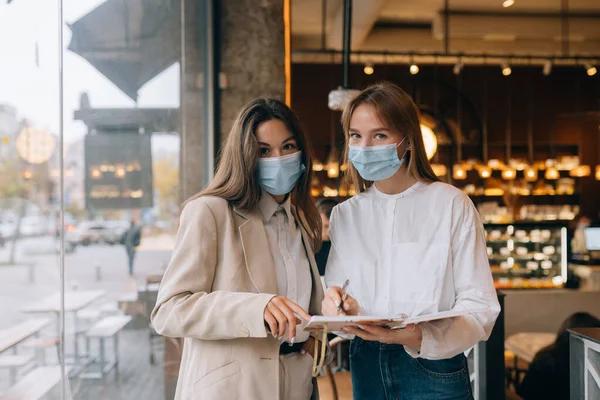 Две предпринимательницы в масках для лица спорят о разных взглядах на работу — стоковое фото