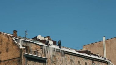 Adam binaların çatısından buz kaldırıyor..