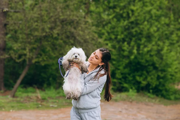 Hermosa mujer sosteniendo un perro en sus brazos — Foto de Stock