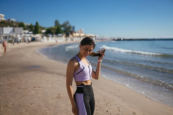 Bella donna in una spiaggia pubblica dopo l'allenamento con look sportivo — Foto Stock