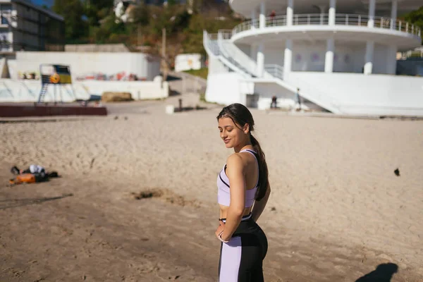 Bella donna in una spiaggia pubblica dopo l'allenamento con look sportivo — Foto Stock