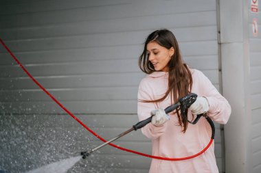 Araba yıkamada mavi araba yıkayan genç bir kadın.