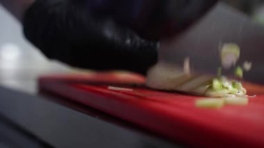 Aşçı tahtadaki soğanları kesiyor.