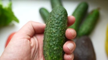 Bir erkeğin eli salatalığı tutar, doğru beslenme kavramı..