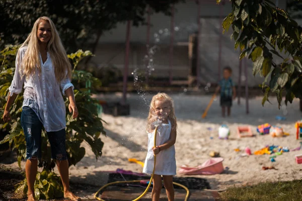 Barn och mamma leker med vatten — Stockfoto