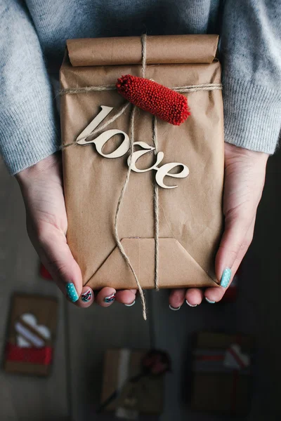 Um presente nas mãos, muitos presentes em um chão  . — Fotografia de Stock