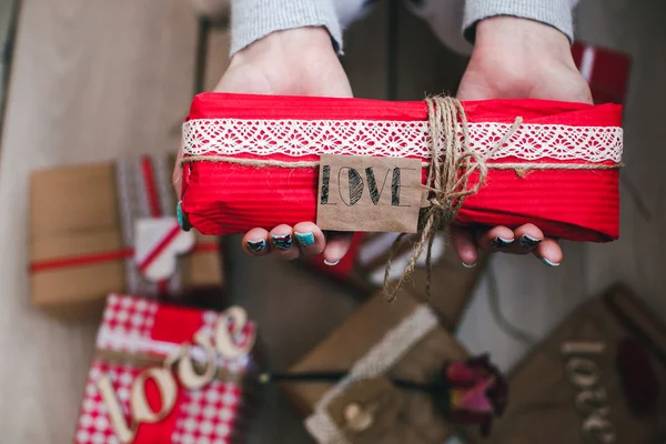 Um presente nas mãos, muitos presentes em um chão  . — Fotografia de Stock