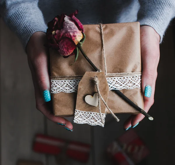 Un regalo en sus manos, muchos en el suelo — Foto de Stock