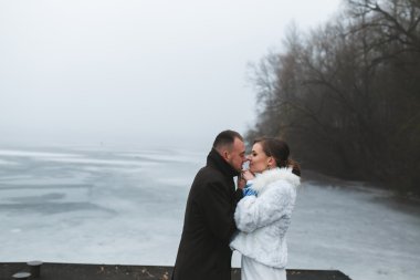 Beautiful couple on the dock in the winter fog. clipart