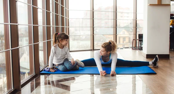 Mother and daughter makeing yoga in the gym