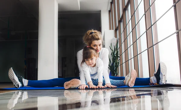 Mother and daughter hugs and stretch in the gym — Stock Photo, Image