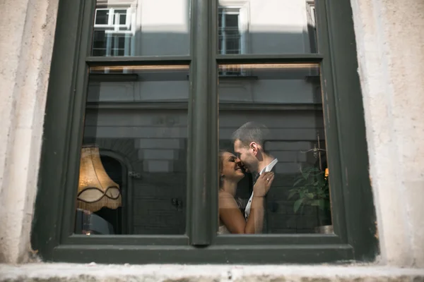 Hochzeitspaar küsst sich im Fenster — Stockfoto