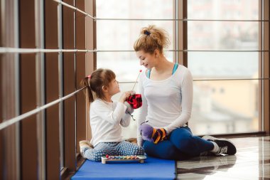Anne ve kızı spor salonunda oyuncaklarla oynuyorlar.