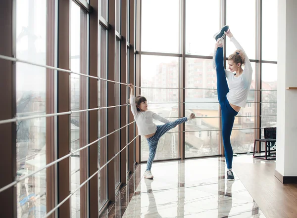 Mother learning daughter to make a high leg strech — Stock Photo, Image