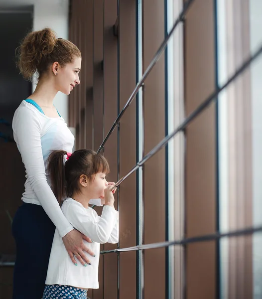 Dos chicas de diferentes edades miran fijamente en una ventana del gimnasio — Foto de Stock