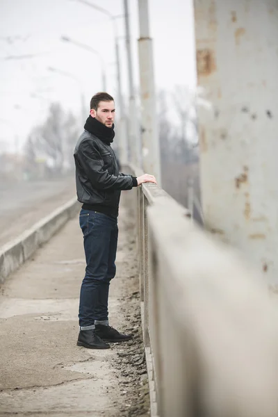 En man klädd i jeans och jacka står nära huvudvägen i f — Stockfoto
